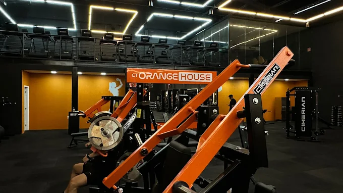Salão de musculação do CT Orange House com máquinas laranja e pretas